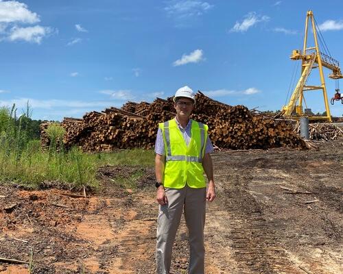 Tony Diaz stands in front of a log pile